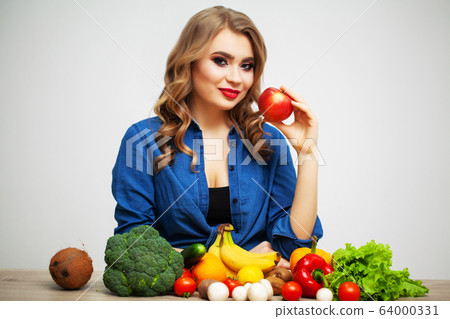 Woman with fresh vegetables and fruits on white wall background Woman with fresh vegetables and fruits on white wall background 64000331