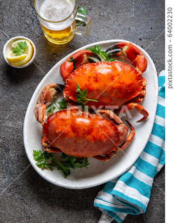 Whole cooked crabs on white plate with lemon and beer. Gray concrete background. Top view Whole cooked crabs on white plate with lemon and beer. Gray concrete background. Top view 64002230