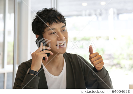 Young man thumbs up while talking on smartphone Young man thumbs up while talking on smartphone 64004638