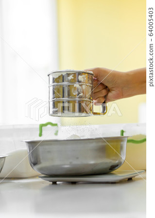 Cooking Baking. Cook sifts the flour close up 64005403
