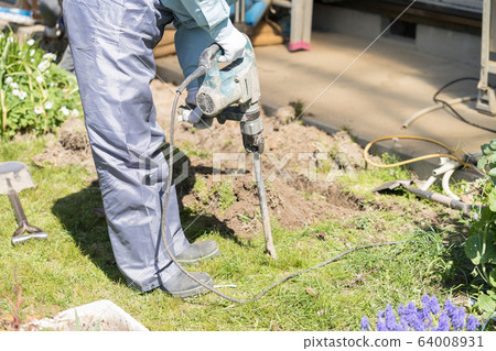Worker digging water pipe groove with electric hammer 64008931
