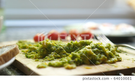 Close up of mashed avocado on a wooden board for guacamole ar bruschetta Close up of mashed avocado on a wooden board for guacamole ar bruschetta 64010081
