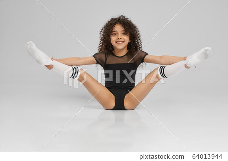 Young female gymnast demonstrating flexibility. 64013944