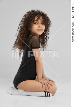 Girl in leotard sitting on studio floor. Girl in leotard sitting on studio floor. 64013946