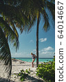 younge man stay near the palm on the ocean beach of tropical island 64014667
