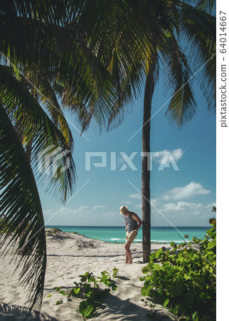 younge man stay near the palm on the ocean beach of tropical island younge man stay near the palm on the ocean beach of tropical island 64014667