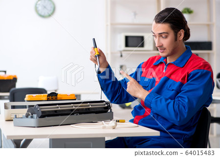 Young repairman repairing air-conditioner at warranty center Young repairman repairing air-conditioner at warranty center 64015483
