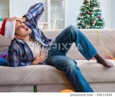 Man having hangover after christmas party 64015894