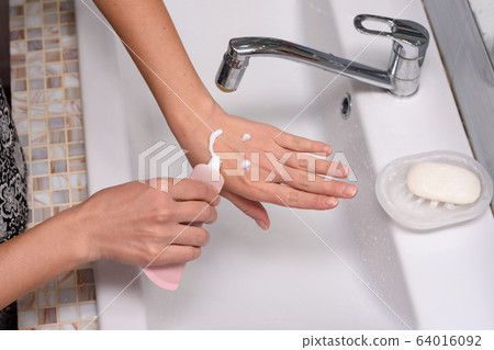 The girl applied the cream to the skin of her The girl applied the cream to the skin of her 64016092