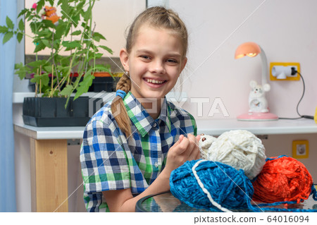 Happy girl embroiders soft toys with thread 64016094