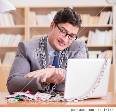 Young businessman addicted to online gambling cards playing in t Young businessman addicted to online gambling cards playing in t 64016152