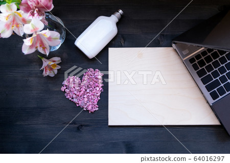 Flat lay home office desk. Working at home women workspace with laptop, flowers bouquet on a dark brown wooden background. Flat lay home office desk. Working at home women workspace with laptop, flowers bouquet on a dark brown wooden background. 64016297