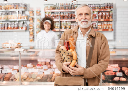 Eldery man holding bag with sausages. 64016299