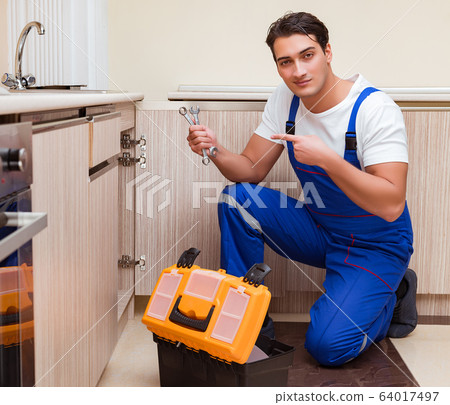 Young repairman working at the kitchen Young repairman working at the kitchen 64017497