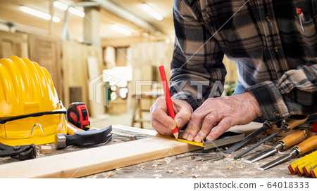 Carpenter at work on wooden boards. Carpentry. 64018333