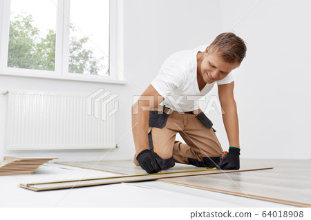 Man installing new wooden laminate flooring Man installing new wooden laminate flooring 64018908