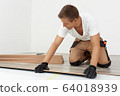 Man installing new wooden laminate flooring 64018939