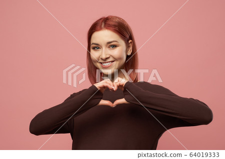 Happy ginger woman with gray eyes with heart made out of palms Happy ginger woman with gray eyes with heart made out of palms 64019333