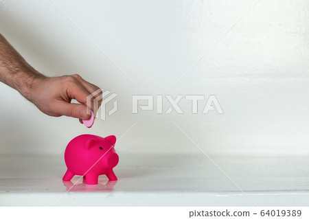 Man hand putting coin in piggy bank. Saving money concept Man hand putting coin in piggy bank. Saving money concept 64019389