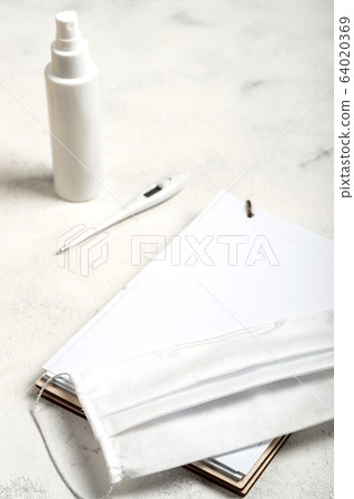 Notebook with place for text and surgical mask, hand sanitizer and digital thermometer on the white background. close-up. Notebook with place for text and surgical mask, hand sanitizer and digital thermometer on the white background. close-up. 64020369