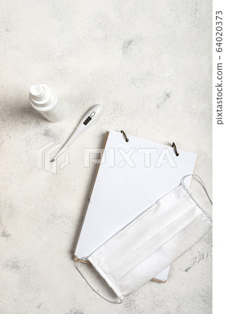 Notebook with place for text and surgical mask, hand sanitizer and digital thermometer on the white background. Concept of the fight against coronovirus, covid -19. Flat lay. 64020373