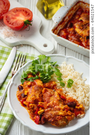 Chicken fillet baked in tomato sauce with corn and beans, served with boiled rice. Mexican style cuisine. Chicken fillet baked in tomato sauce with corn and beans, served with boiled rice. Mexican style cuisine. 64021547