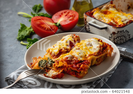 Spinach and ricotta stuffed cannelloni baked in tomato sauce. Spinach and ricotta stuffed cannelloni baked in tomato sauce. 64021548