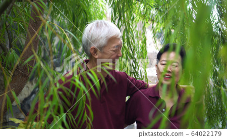 Happy retired Asian elder couple laughing under green willow tree background Happy retired Asian elder couple laughing under green willow tree background 64022179