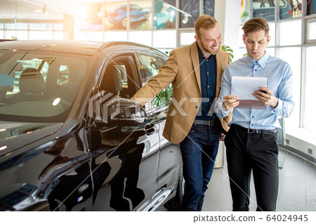 young consultant talking about features of new car young consultant talking about features of new car 64024945