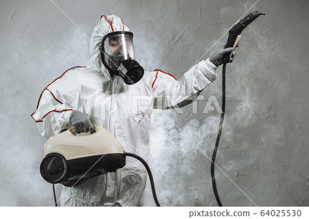 disinfector in protective suit conducts disinfection 64025530