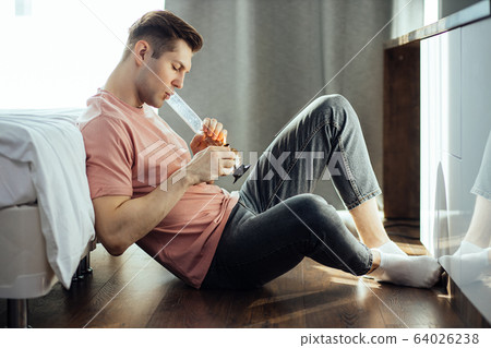 man smokes bong cannabis weed at home 64026238