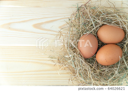 Fresh brown chicken eggs in hay nest on blue 64026621