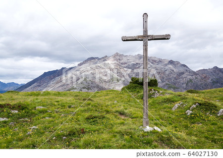 Cross on top of the mountains of Livigno Alps on the border between Italy and Switzerland, cloudy summer day, Italy Cross on top of the mountains of Livigno Alps on the border between Italy and Switzerland, cloudy summer day, Italy 64027130