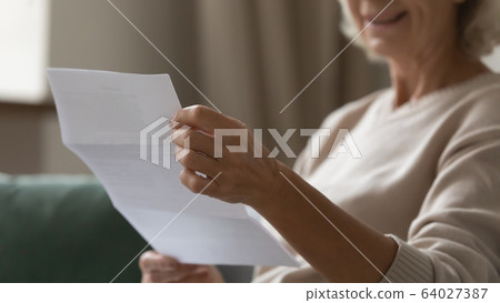 Close up wrinkled female hands holding paper document. Close up wrinkled female hands holding paper document. 64027387