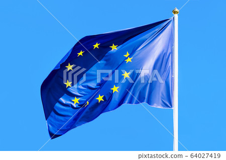 The European Union flag on the background of blue sky. The European Union flag on the background of blue sky. 64027419