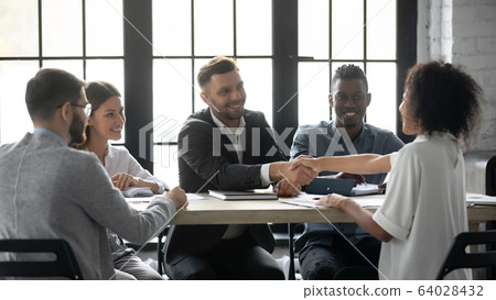 Successful businessman in suit shaking hand of african american businesswoman. 64028432