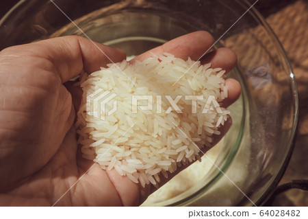 close up Hand holds grains of rice in glass jar close up Hand holds grains of rice in glass jar 64028482
