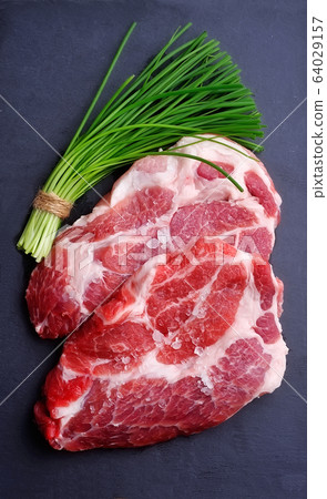 Crude meat with green onion on black board. Crude meat with green onion on black board. 64029157