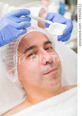 Man lies on spa and has transparent facial mask 64029211