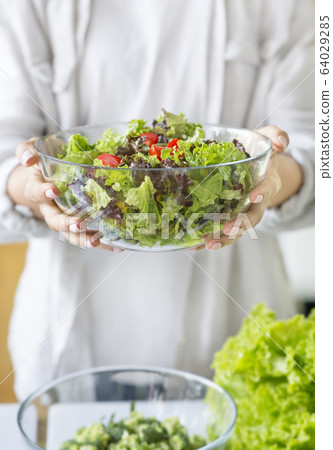 Unrecognizable woman preparing a green mixed salad in the kitchen Unrecognizable woman preparing a green mixed salad in the kitchen 64029285