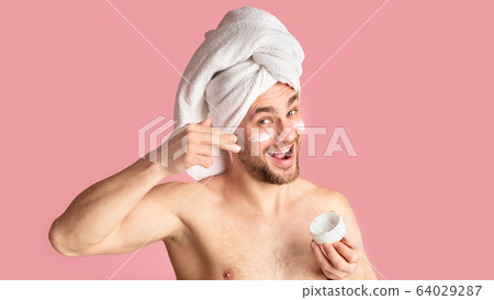 Emotional millennial guy funny smears face cream Emotional millennial guy funny smears face cream 64029287