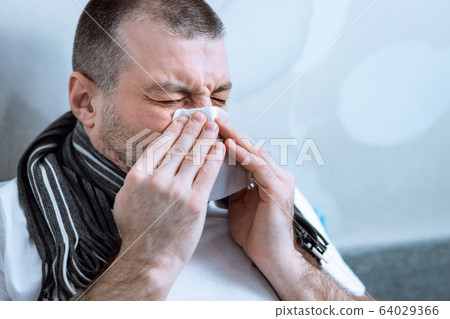 Man Blowing Nose In Tissue Having Fever Lying In Bed 64029366