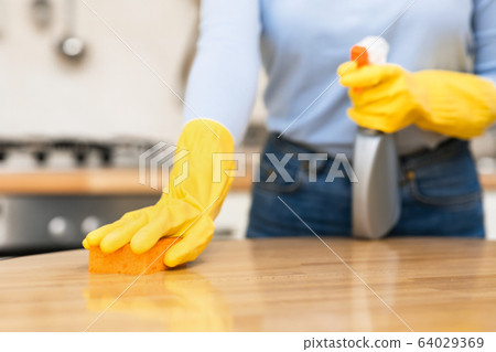 Young woman cleaning kitchen table using spray and sponge Young woman cleaning kitchen table using spray and sponge 64029369