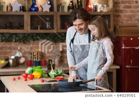 Dad teaching his cute daughter how to cook food on pan Dad teaching his cute daughter how to cook food on pan 64029501