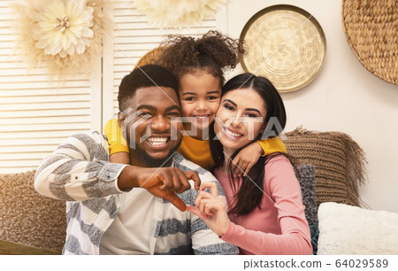 Smiling millennial family on sofa at home Smiling millennial family on sofa at home 64029589
