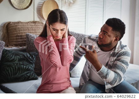 Husband scolds wife. Woman covers her ears Husband scolds wife. Woman covers her ears 64029622