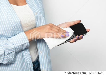 Unrecognizable Woman Disinfecting Smartphone Over White Studio Background, Cropped 64029623