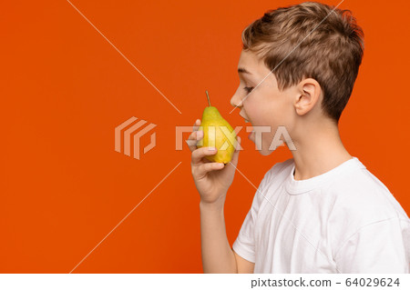 Teen boy biting fresh pear, side view Teen boy biting fresh pear, side view 64029624