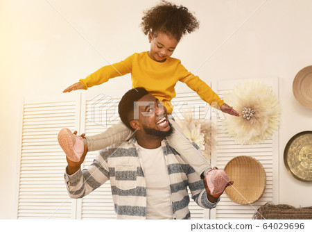 African american dad have fun with daughter holding her on shoulders 64029696