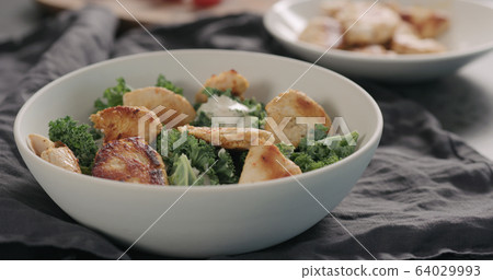 making caesar salad with kale and turkey in white bowl, add turkey 64029993